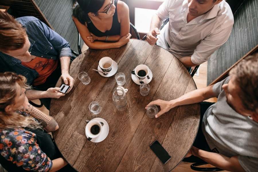 A unique coffee table surrounded by friends sharing coffee and conversation.
